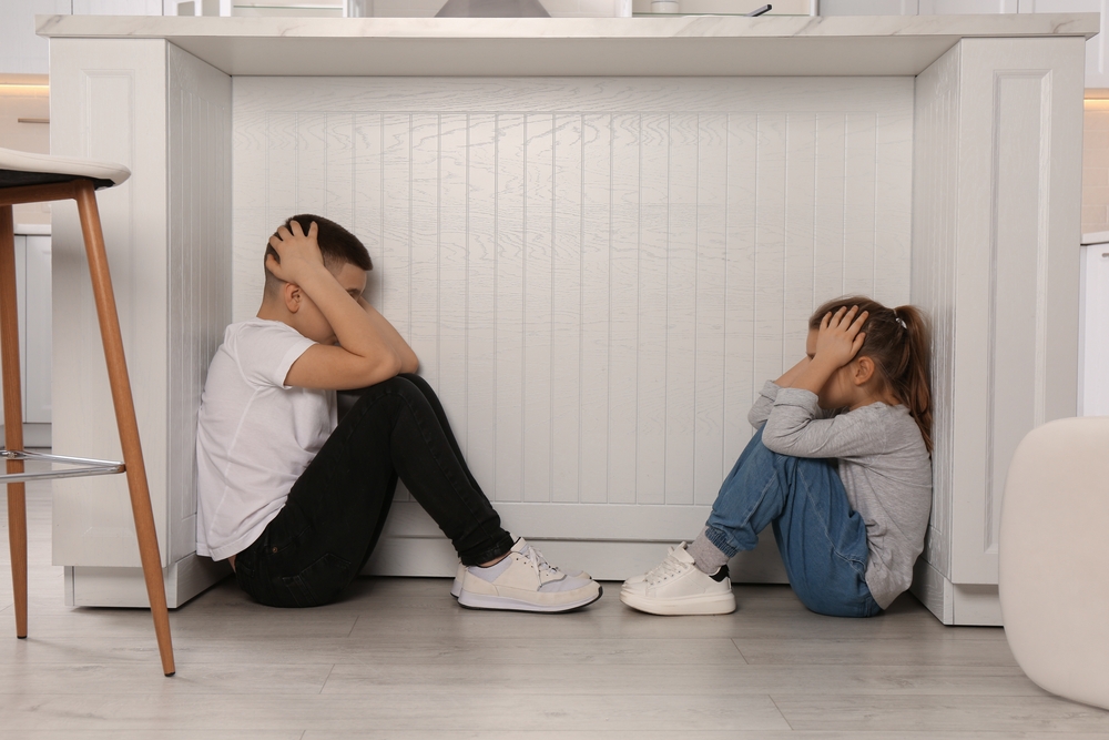 Scared,Children,Hiding,Under,Table,In,Kitchen,During,Earthquake