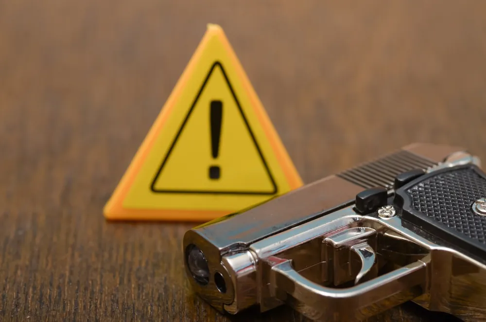The,Juxtaposition,Of,The,Warning,Sign,And,The,Gun,Symbolizes