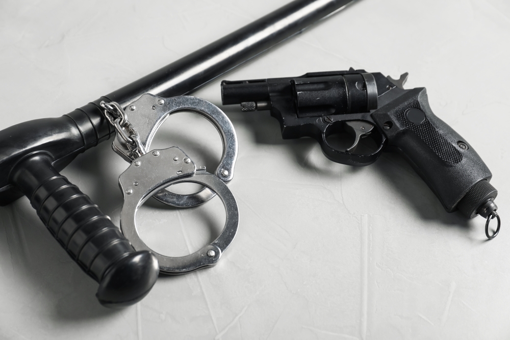 Police,Baton,,Handcuffs,And,Gun,On,Light,Grey,Table,,Closeup