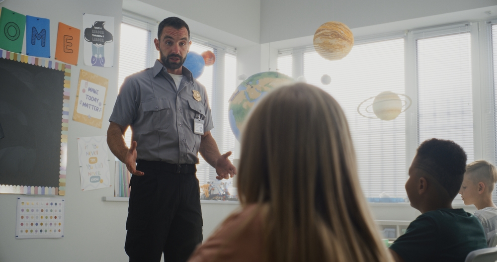 Male,Policeman,Visiting,Classroom,,Giving,Lecture,To,Curious,Primary,School